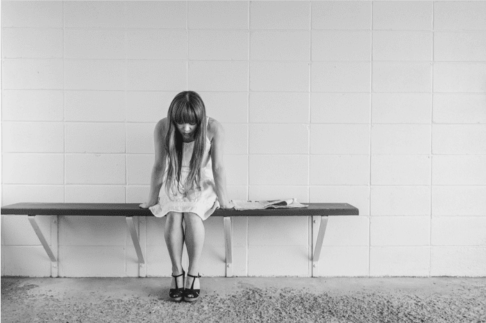black and white photo of young girl sitting on a bench